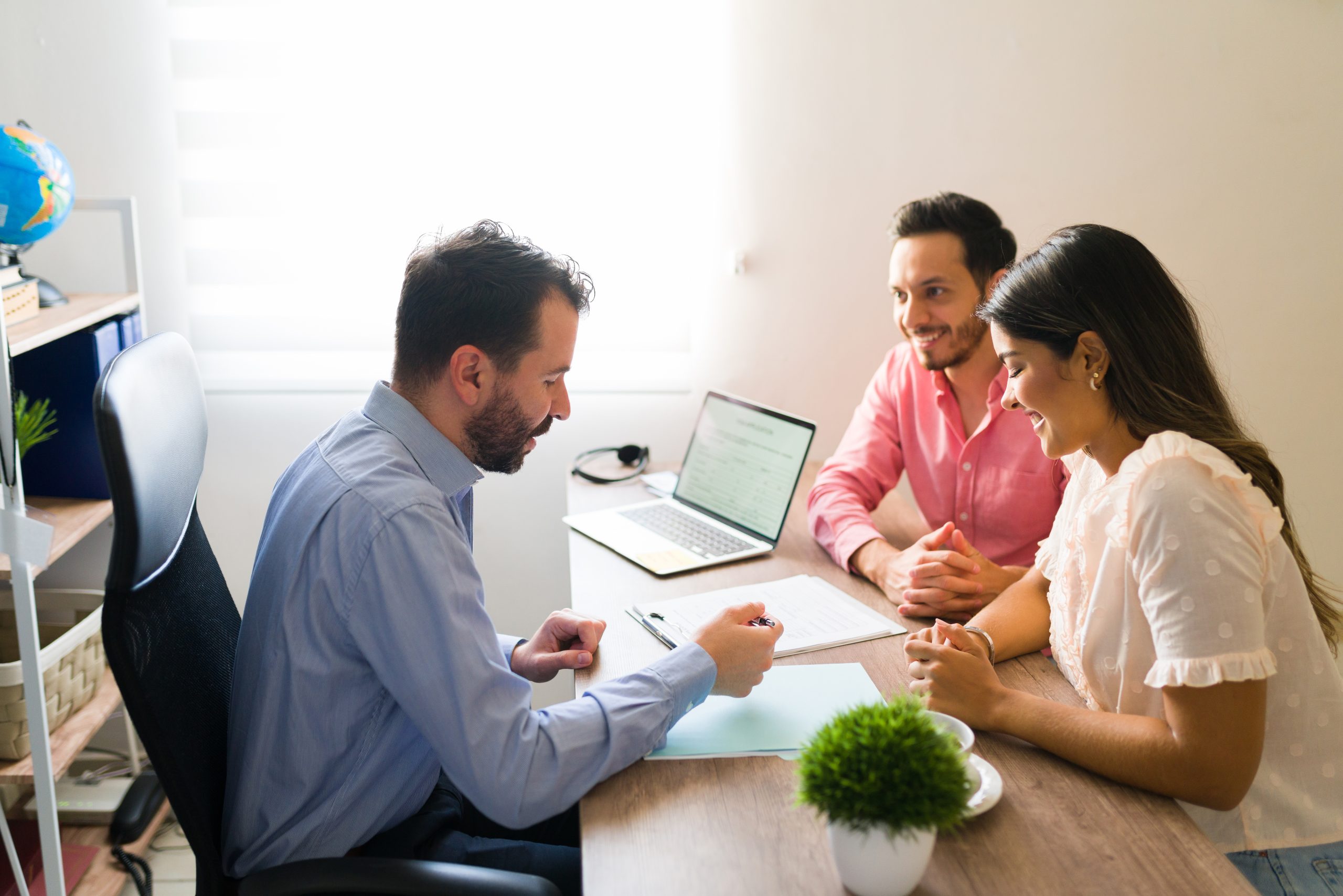 Hispanic couple buying flights with a sales agent